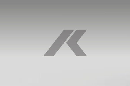 Logotipo geométrico gris que se asemeja a dos flechas consecutivas, centradas en un fondo gris degradado.
