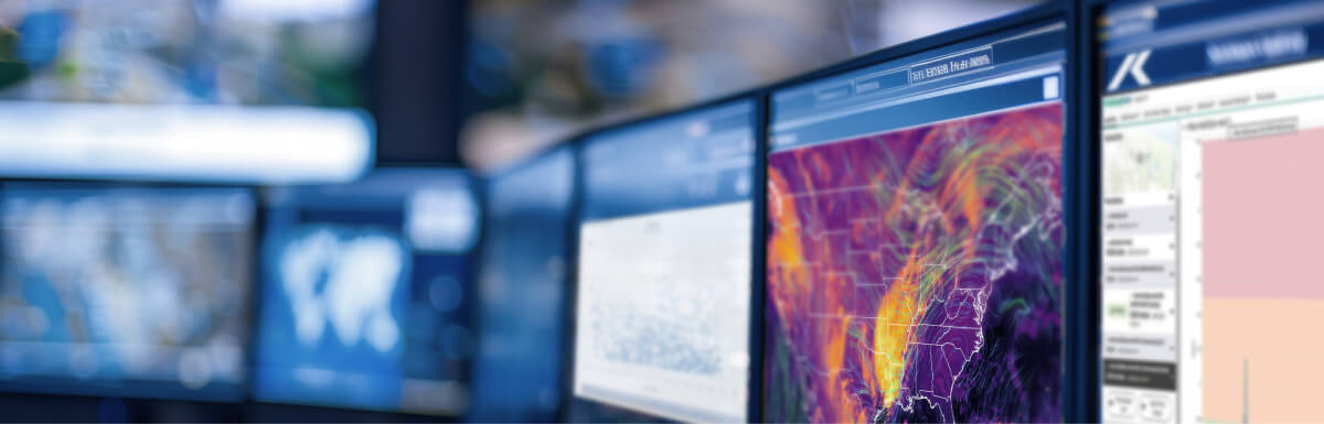 Pantallas con mapas meteorológicos y datos analíticos en un centro de monitoreo.