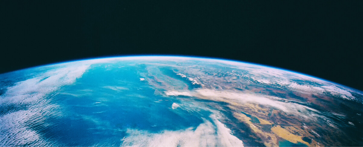 Vista de la Tierra desde el espacio con océanos azules y continentes parcialmente cubiertos por nubes.